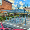 cycle shelter outdoors with glass and metal roof and racks installed