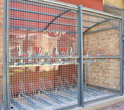 metal bike shelter with mesh sliding fence outside of a commercial building