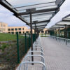 Metal and glass cycling shelter outside of a school with toastrack installed