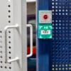 close up of push to exit button on blue and white perforated mesh fencing