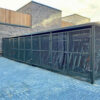 bike storage with mesh swing doors and metal fascia outside of a brick building