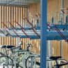 Modern indoor bicycle parking facility with empty racks and a few parked bicycles, featuring wooden panel walls and a clear focus on orderly, secure storage.