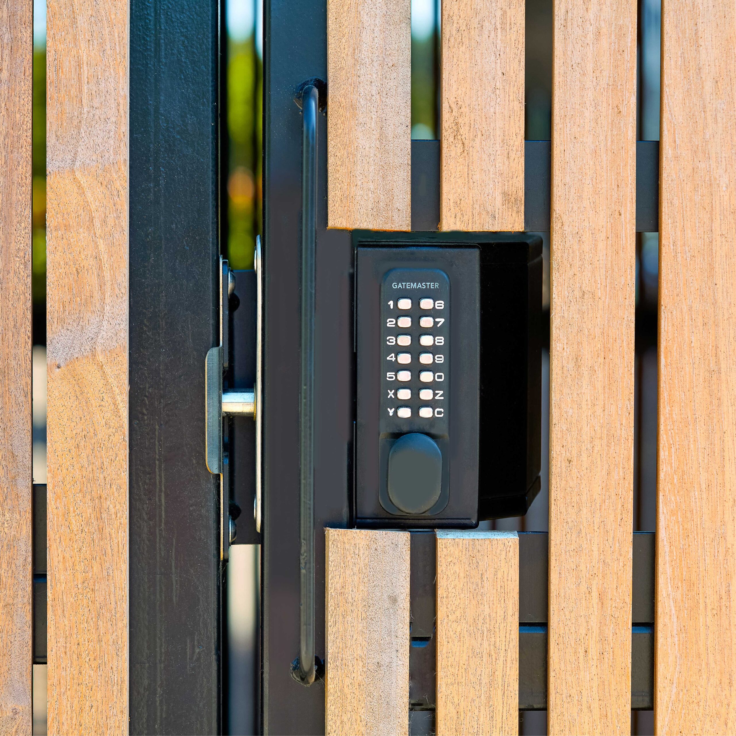 A keypad lock mounted on a wooden gate, showing a sturdy metal latch and a black keypad with buttons labeled with numbers and letters.