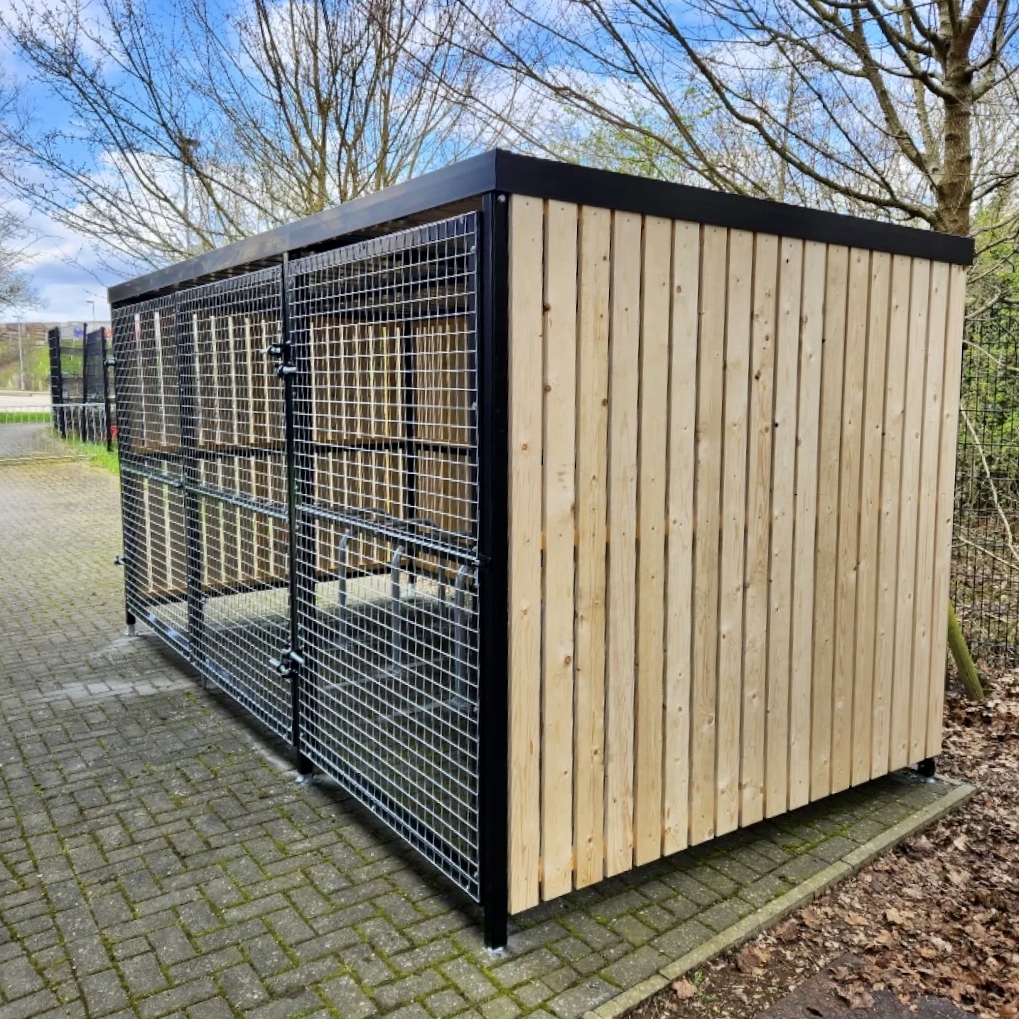 wooden bike shelter outside with mesh fencing