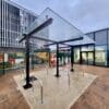 a bike canopy shelter with bike rack with metal bars in front of a building