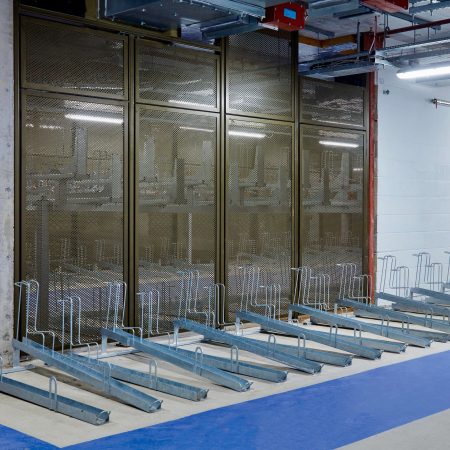 Perforated mesh fencing installed in an underground cycle storage facility with single tier cycle racks installed