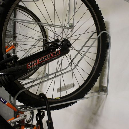 Close up shot of Vertical Bike Rack on a white wall with a bike securely stored in them